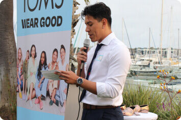 A person from the Venice Family Clinic speaking into a microphone reading from a piece of paper.